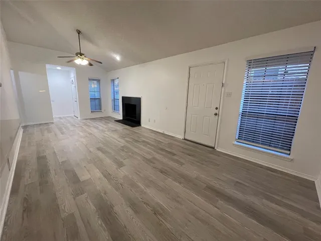 a view of empty room with wooden floor and ceiling fan