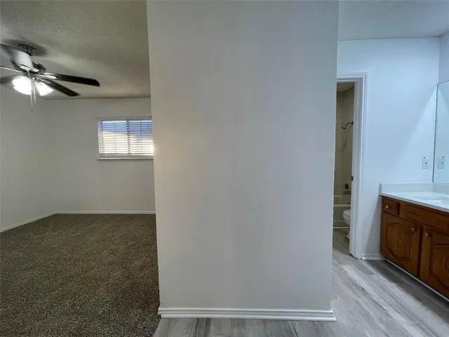 an empty room with windows fireplace and fan