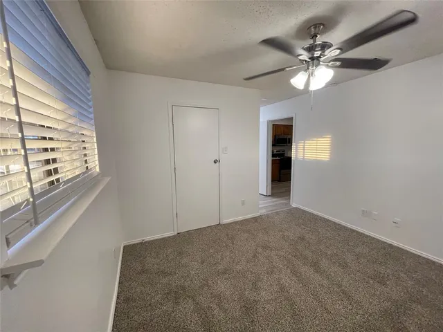 en empty room with windows and chandelier fan