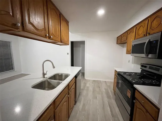 a kitchen with granite countertop stainless steel appliances a sink a stove and cabinets