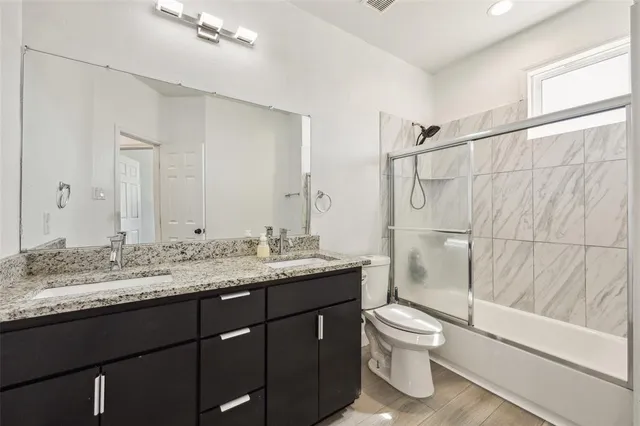 a bathroom with a granite countertop sink toilet a mirror and shower