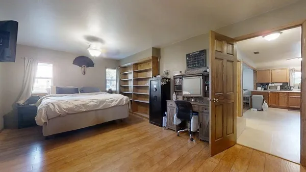 a bedroom with a bed dresser and a wooden floor
