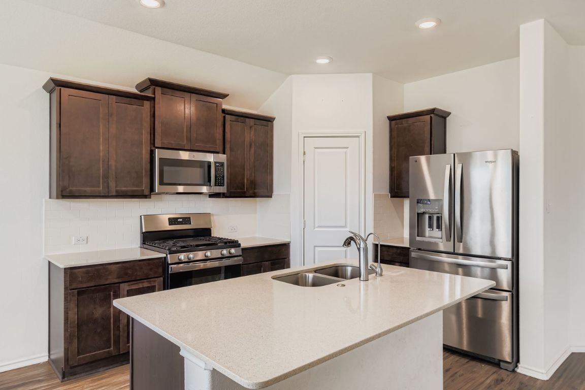 210 Montego Street Hutto, TX 78634 - Photo 11 of 29 a kitchen with a appliances a sink and a refrigerator