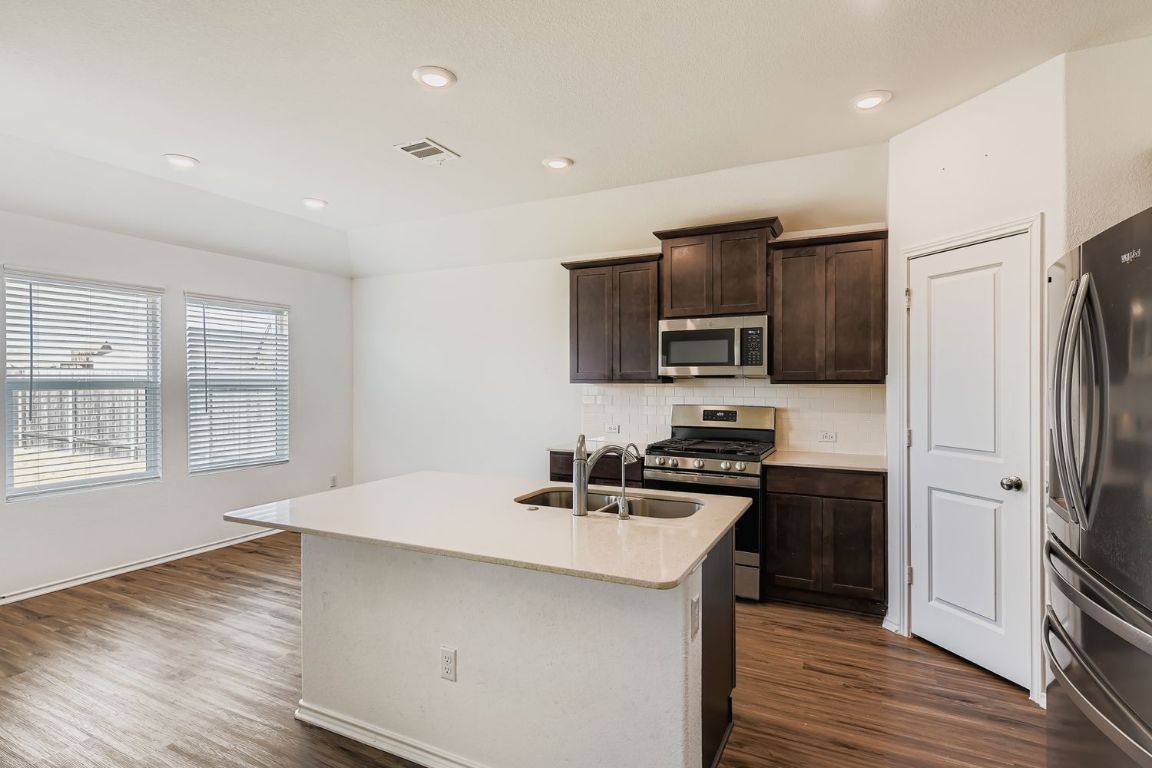 210 Montego Street Hutto, TX 78634 - Photo 12 of 29 a kitchen that has a sink stainless steel appliances a counter space and a window