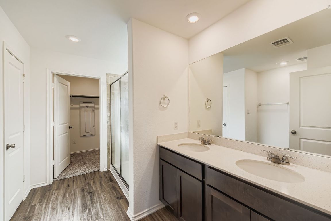 210 Montego Street Hutto, TX 78634 - Photo 16 of 29 a bathroom with a double vanity sink a mirror and a shower