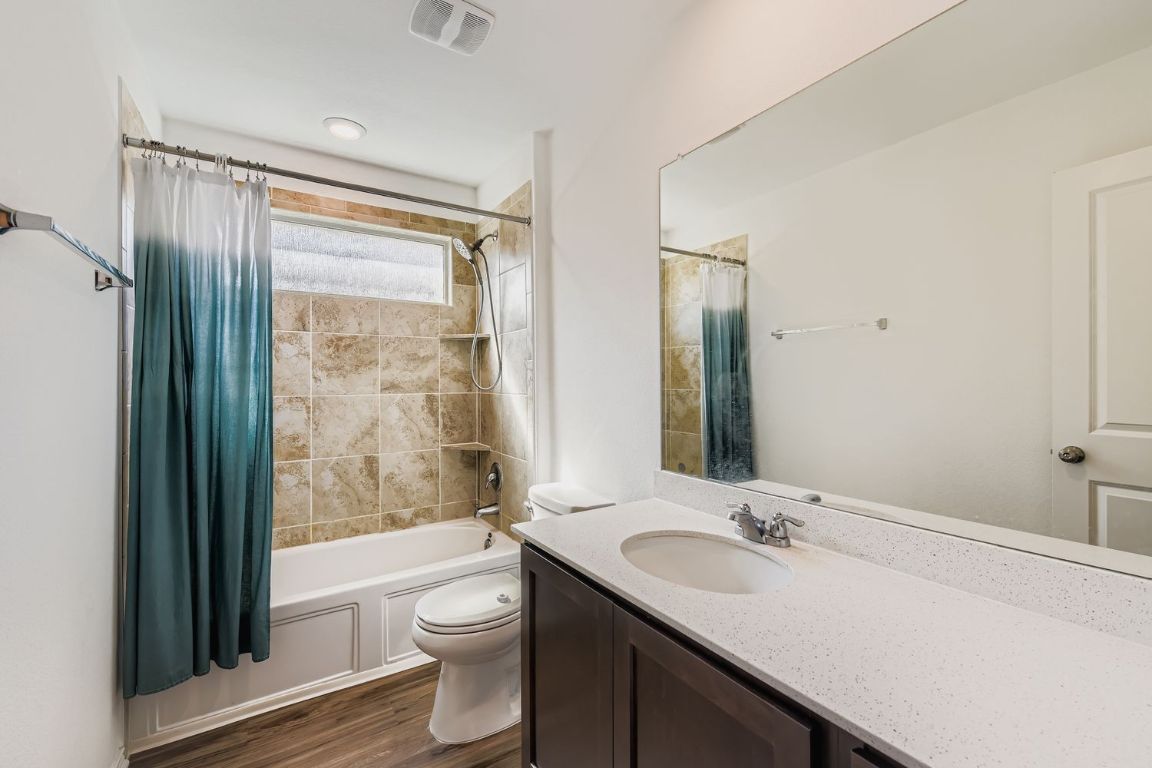 210 Montego Street Hutto, TX 78634 - Photo 20 of 29 a bathroom with a granite countertop sink toilet a mirror and shower