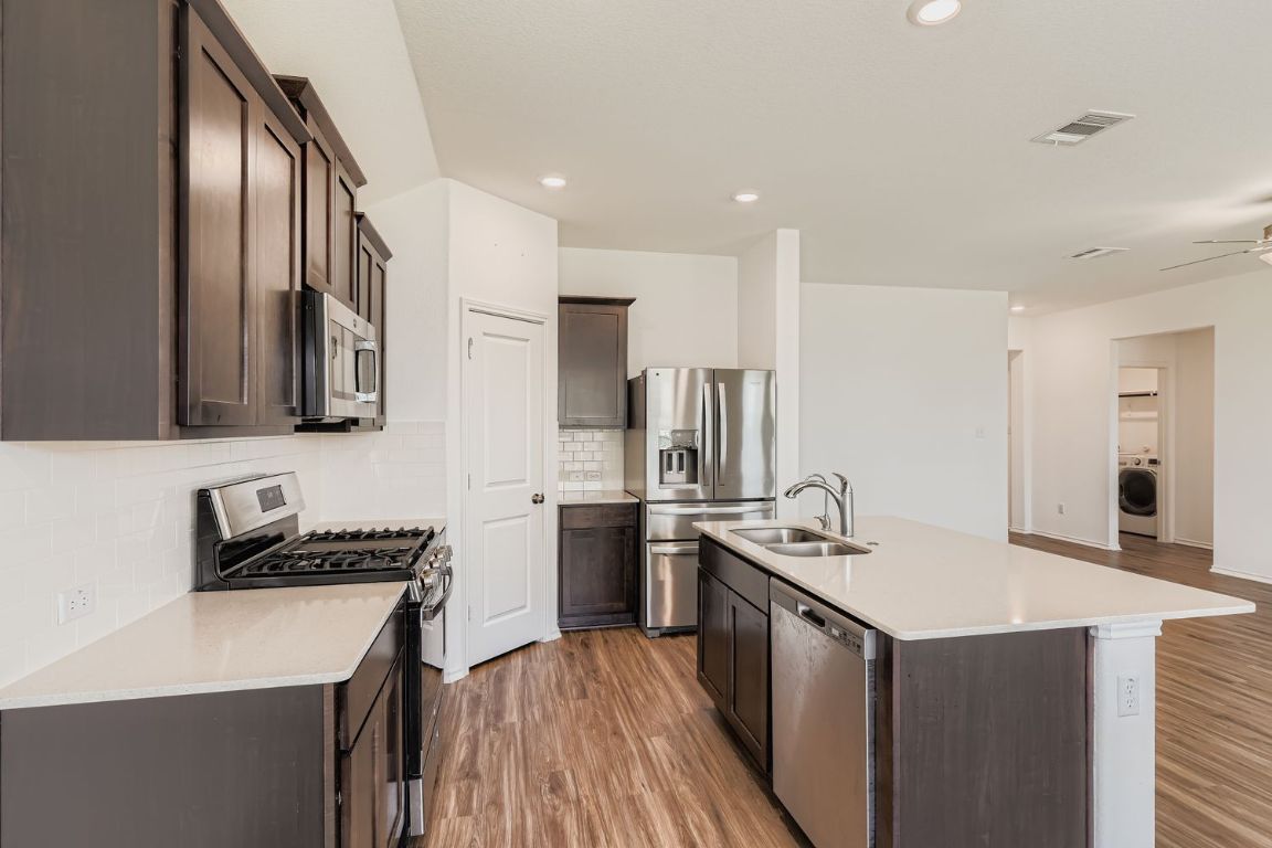 210 Montego Street Hutto, TX 78634 - Photo 10 of 29 a kitchen with stainless steel appliances granite countertop a sink stove and refrigerator
