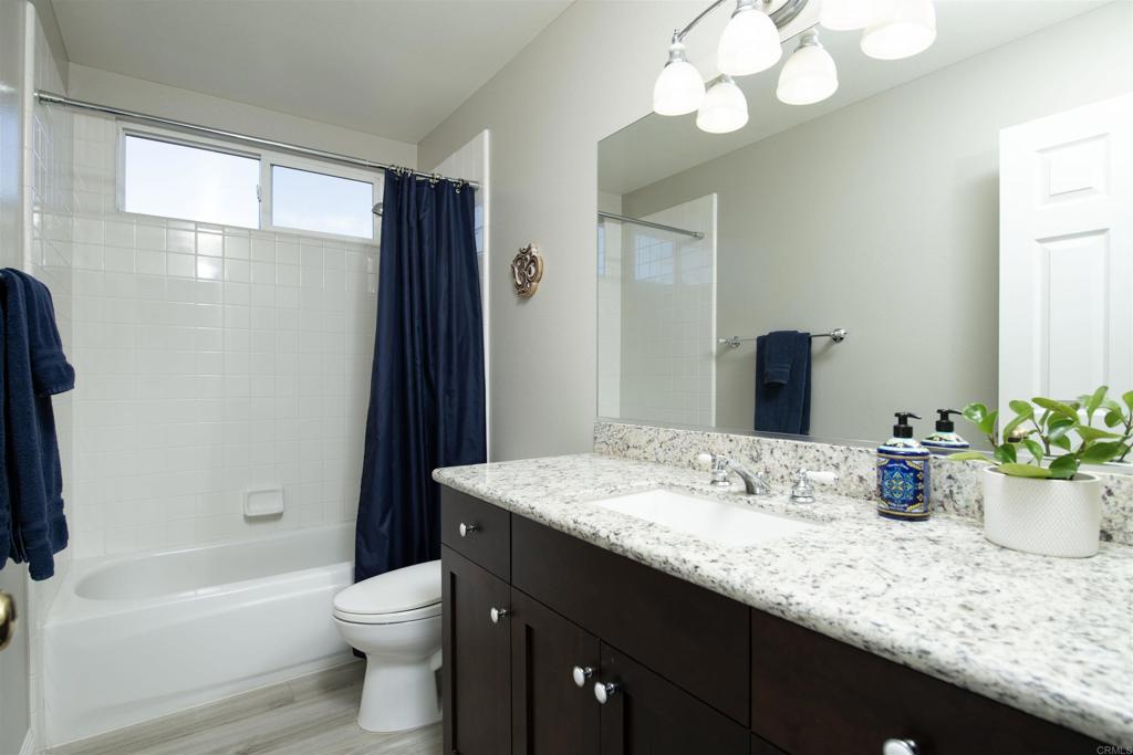 1677 Mission Meadow Drive Oceanside, CA 92057 - Photo 15 of 48 a bathroom with a granite countertop sink a toilet a mirror a bathtub and shower