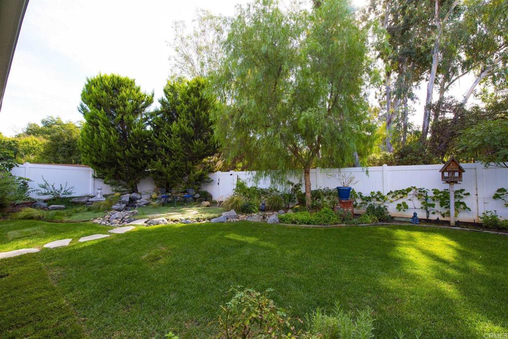 1677 Mission Meadow Drive Oceanside, CA 92057 - Photo 25 of 48 a backyard of a house with table and chairs plants and large tree