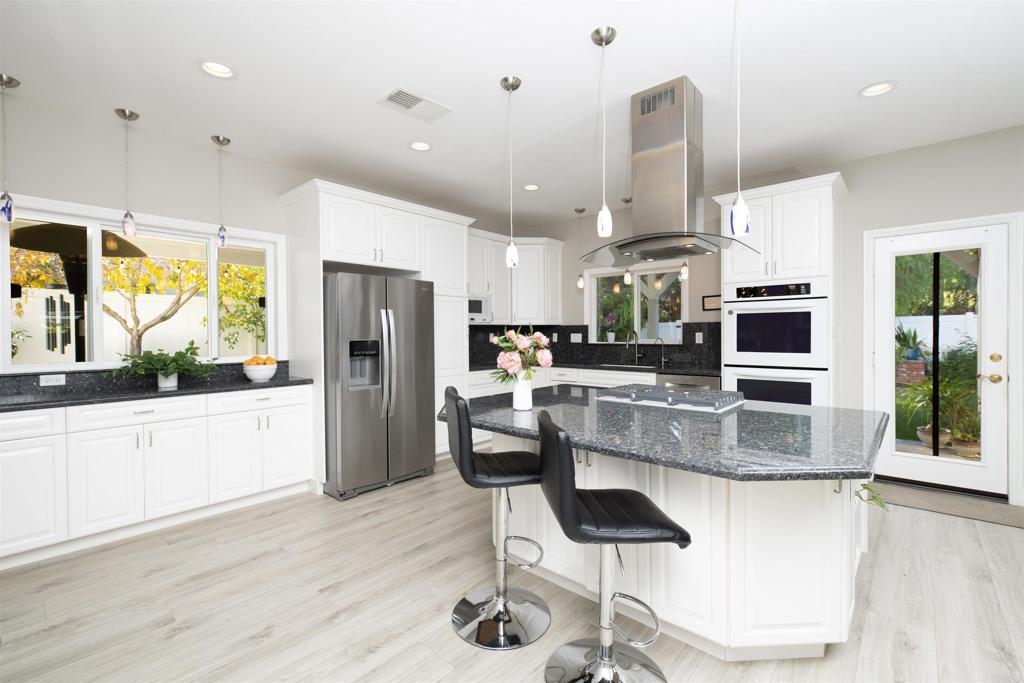 1677 Mission Meadow Drive Oceanside, CA 92057 - Photo 9 of 48 a kitchen with stainless steel appliances granite countertop a refrigerator a stove a sink a dining table and chairs with wooden floor