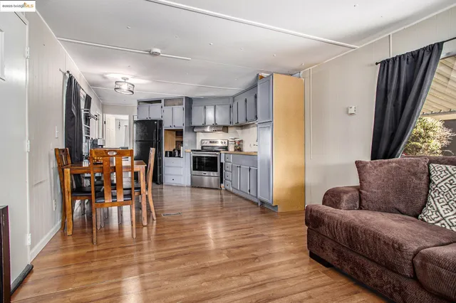a living room with stainless steel appliances furniture and a view of kitchen