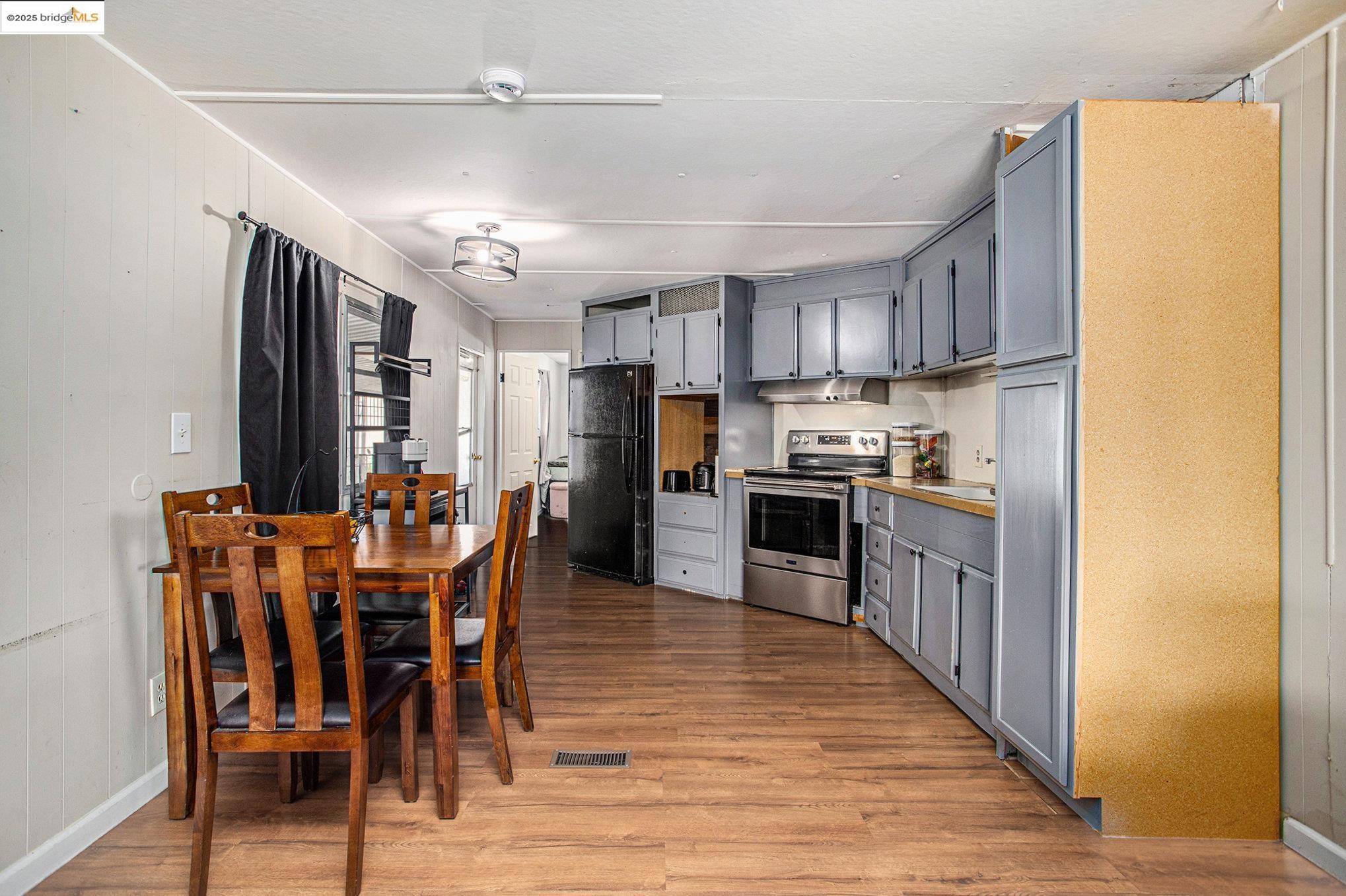 3301 Buchanan Road, Unit 118 Antioch, CA 94509 - Photo 5 of 15 Kitchen featuring gray cabinetry, stainless steel electric stove, light wood finished floors, freestanding refrigerator, and under cabinet range hood