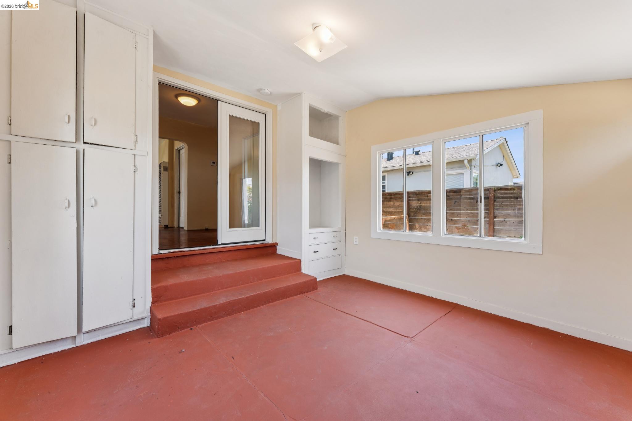 2879 Rheem Avenue Richmond, CA 94804 - Photo 24 of 45 Room featuring painted concrete flooring, a large window, built-in storage cabinetry, built-in shelving with drawers, and a sliding glass door