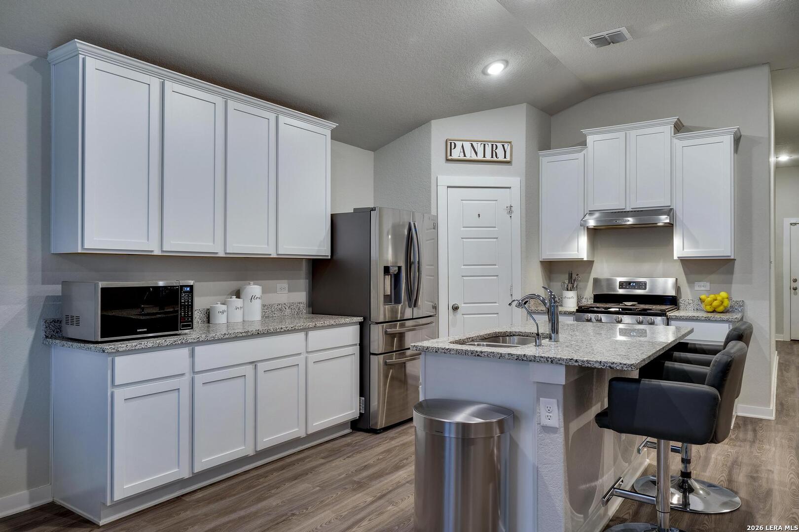 6910 Shiraz Way Converse, TX 78109 - Photo 9 of 25 a kitchen with stainless steel appliances a stove a sink a refrigerator a cabinets and wooden floor