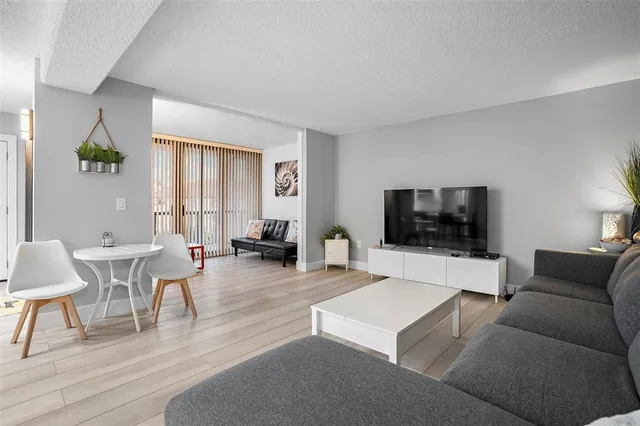 a living room with furniture a flat screen tv and a window