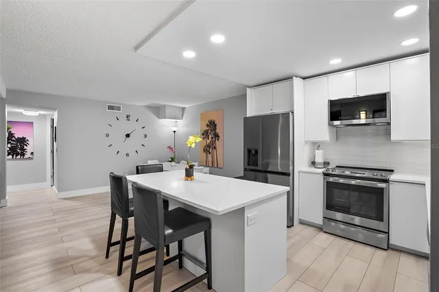 a kitchen with stainless steel appliances kitchen island granite countertop a dining table and chairs