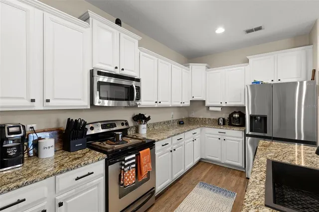 a kitchen with granite countertop a sink a stove and refrigerator