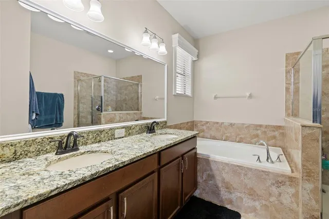 a bathroom with a granite countertop bathtub sink double and mirror
