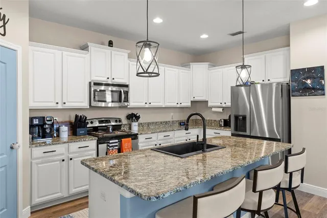 a kitchen with stainless steel appliances granite countertop a sink refrigerator and cabinets