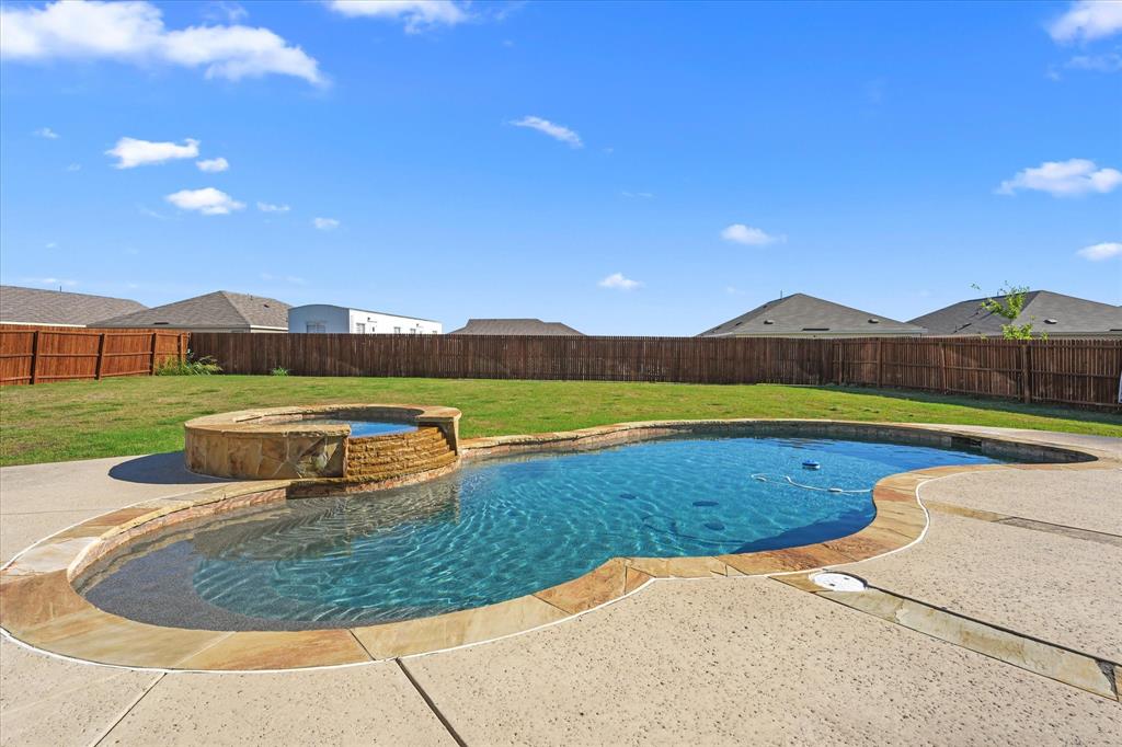 2044 Longbridge Road Forney, TX 75126 - Photo 29 of 40 Inviting backyard featuring a freeform swimming pool, integrated spa with stone surround, perimeter concrete decking, and a privacy fence
