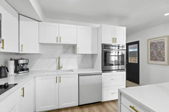 a kitchen with white cabinets and sink