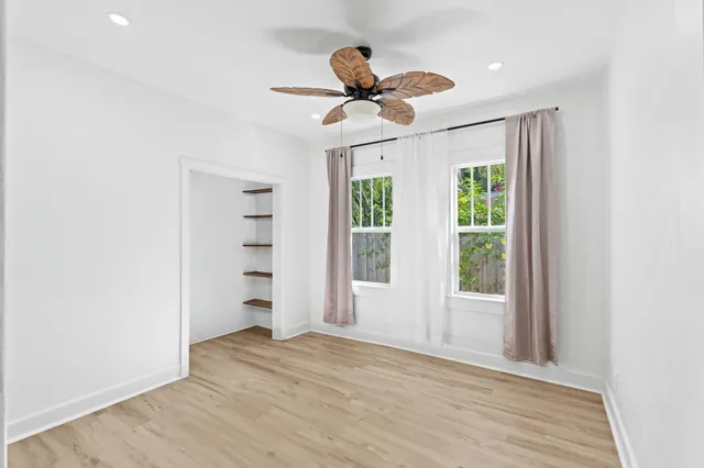 a view of empty room with wooden floor and fan