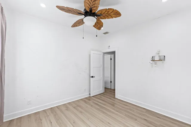 an empty room with wooden floor fan and window