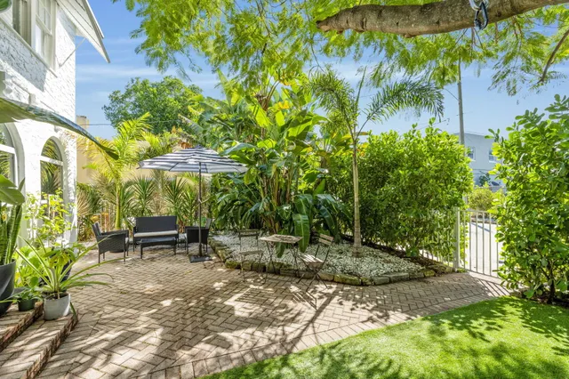 a backyard of a house with table and chairs under an umbrella