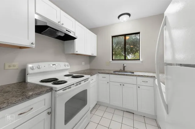 a kitchen with granite countertop white cabinets white stainless steel appliances a sink and a stove