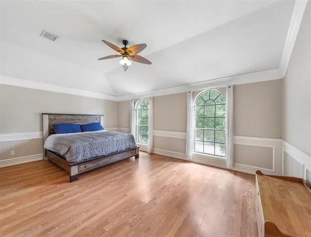 a bedroom with a large bed and wooden floor