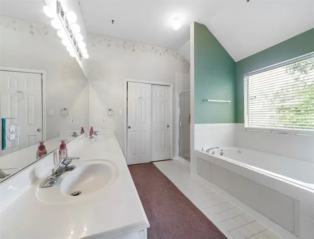 a spacious bathroom with a tub sink and mirror