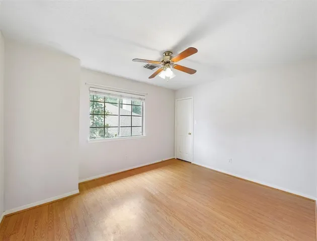 an empty room with a window and a fan