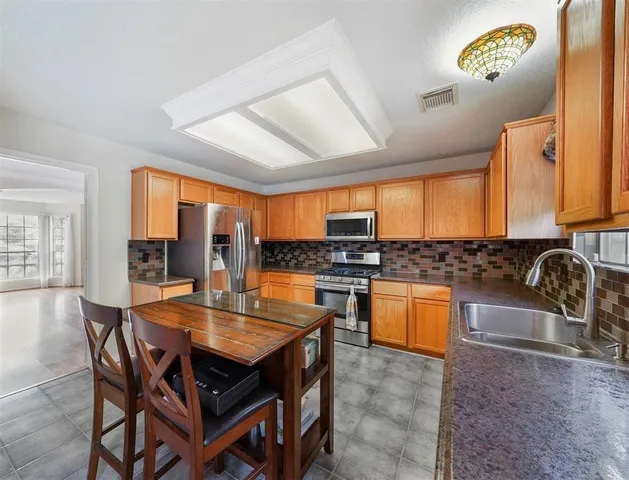 a dining hall with stainless steel appliances granite countertop a stove a sink a dining table and chairs