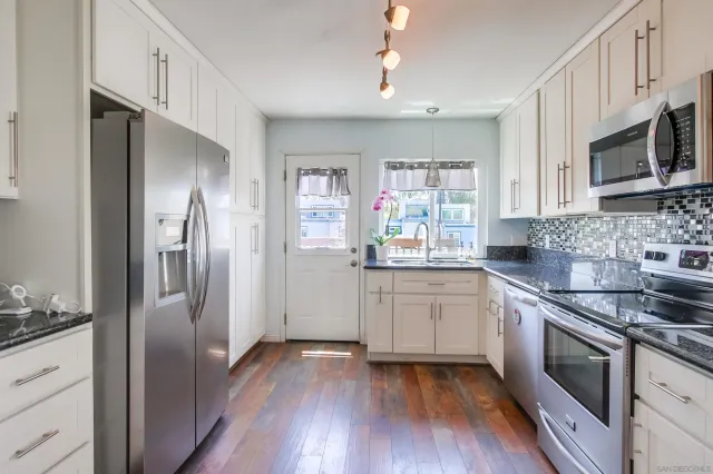 a kitchen with granite countertop a refrigerator stove and sink
