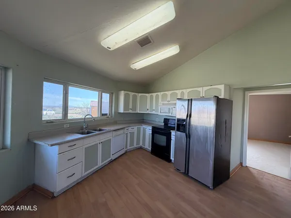 a kitchen with stainless steel appliances granite countertop a stove a refrigerator a sink dishwasher and wooden cabinets with wooden floor