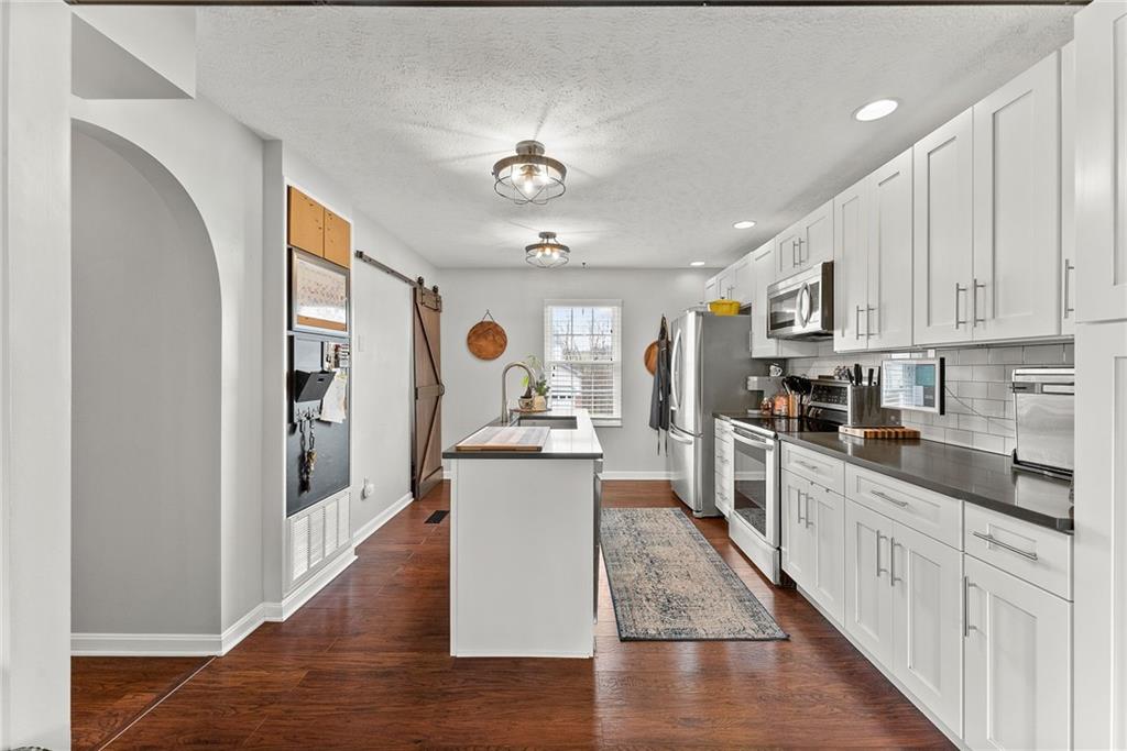 1163 Valleyview Drive Lawrence, PA 15055 - Photo 6 of 25 a kitchen with stainless steel appliances granite countertop a refrigerator a stove top oven a sink dishwasher and white cabinets with wooden floor