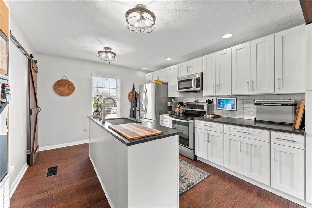 1163 Valleyview Drive Lawrence, PA 15055 - Photo 8 of 25 a kitchen with stainless steel appliances granite countertop a stove top oven a sink a refrigerator white cabinets and wooden floor