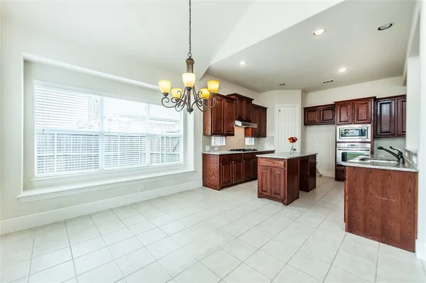 a room with stainless steel appliances kitchen island granite countertop a refrigerator and a stove top oven