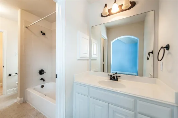 a bathroom with a tub a sink and mirror