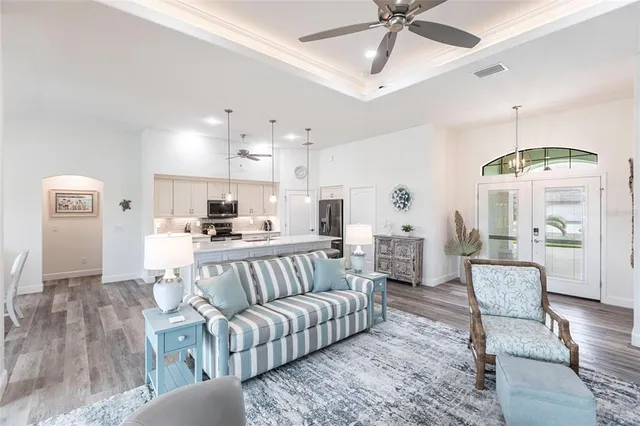a living room with furniture kitchen view and a chandelier