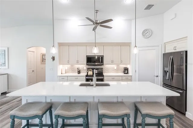 a kitchen with stainless steel appliances a dining table chairs and refrigerator