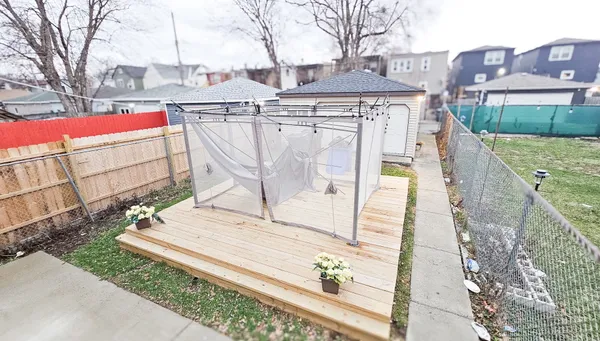 a view of a white house with a large tree and wooden fence