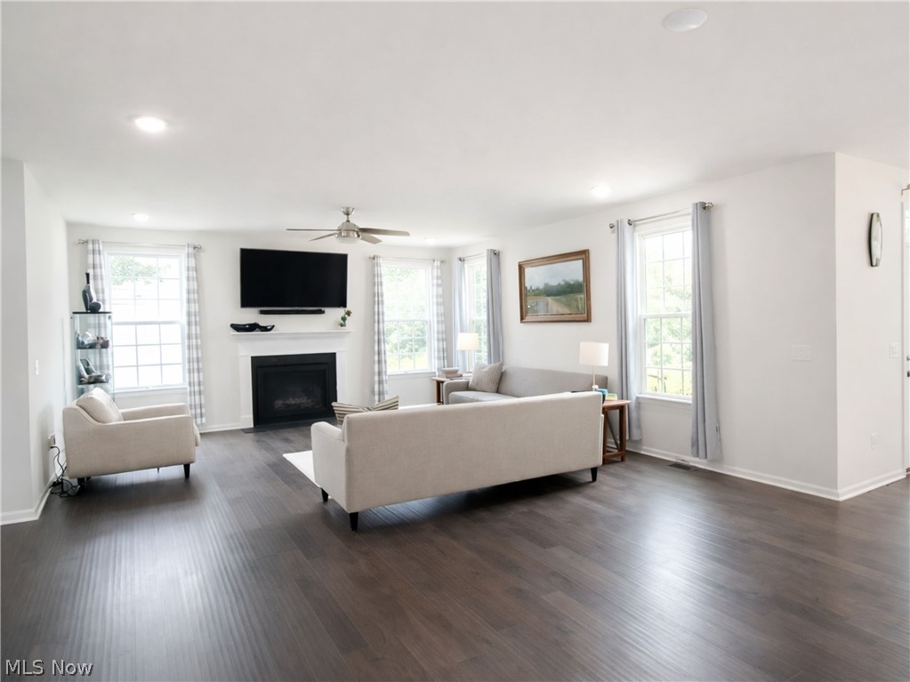 4509 Millbrook Way Akron, OH 44321 - Photo 11 of 27 Spacious living area featuring dark wood-finish flooring, a white mantel fireplace, multiple windows providing natural light, recessed lighting, and a ceiling fan
