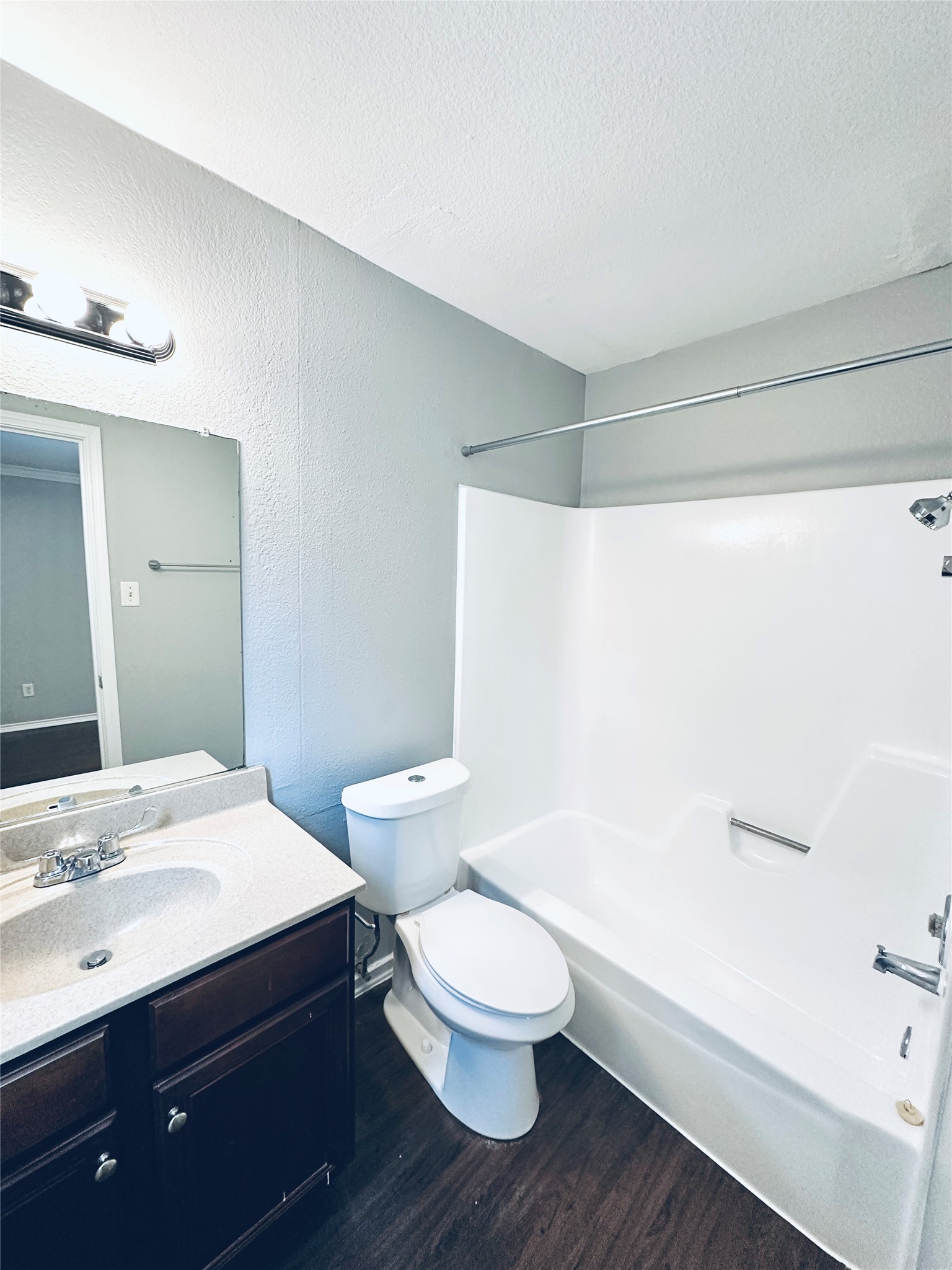 805 South Center Street, Unit 108 Austin, TX 78704 - Photo 11 of 14 Bathroom with shower combination, vanity, dark wood finished floors, a textured ceiling, and a textured wall