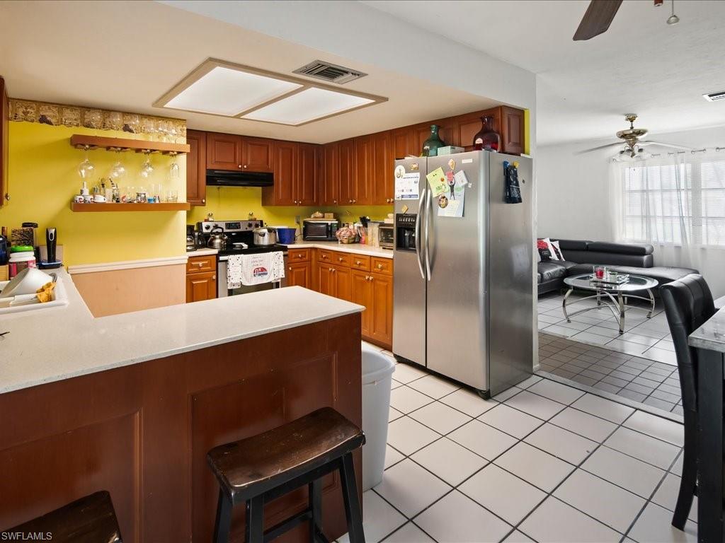 4865 22nd Avenue Southwest Naples, FL 34116 - Photo 7 of 20 a kitchen with stainless steel appliances a dining table chairs and a refrigerator