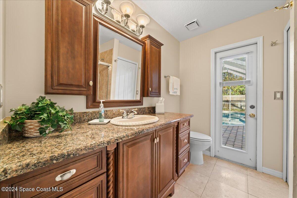 4360 Canard Road Melbourne, FL 32934 - Photo 29 of 54 a bathroom with a granite countertop sink a toilet and a mirror