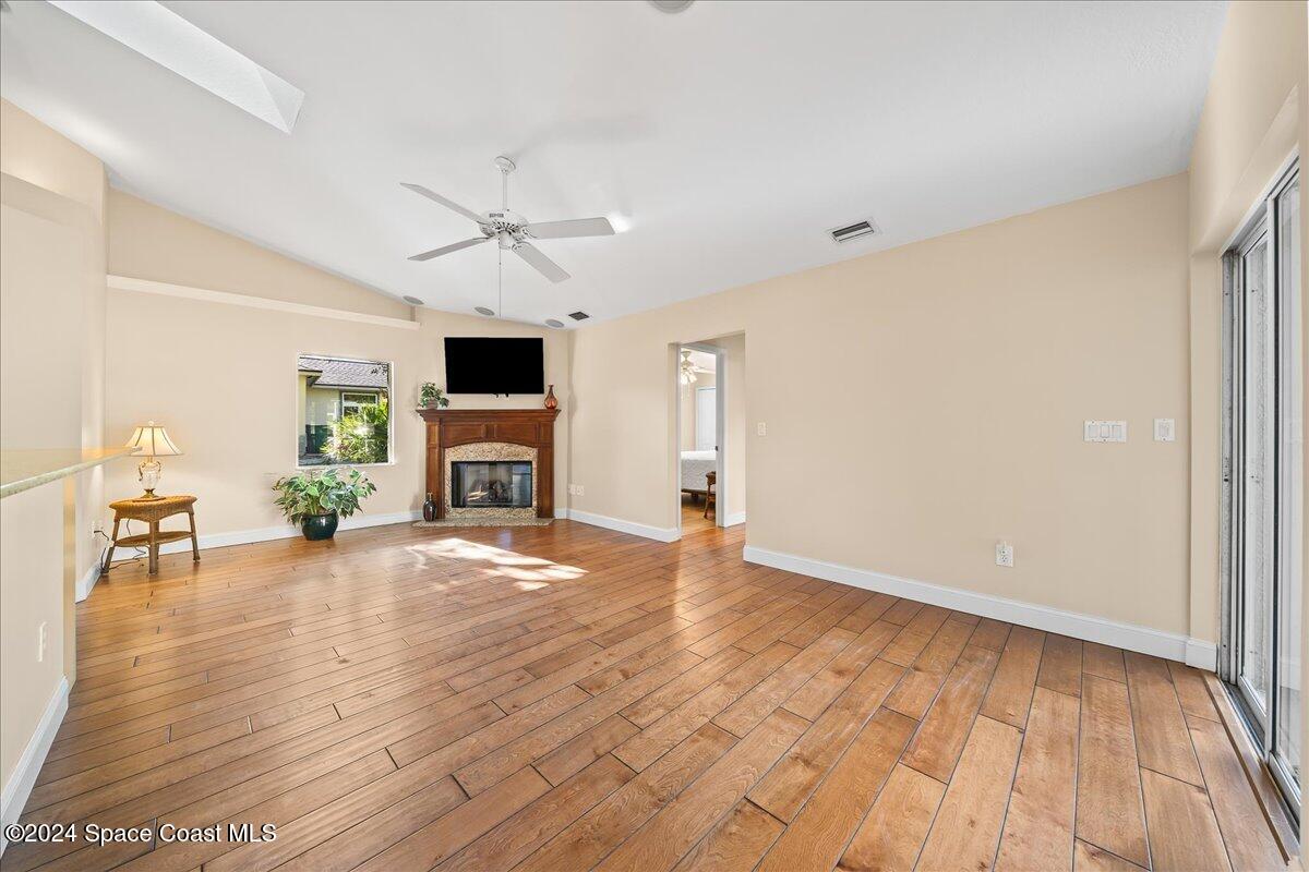 4360 Canard Road Melbourne, FL 32934 - Photo 10 of 54 an empty room with fireplace wooden floor chandelier fan and windows
