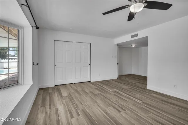 a view of an empty room with wooden floor and a window