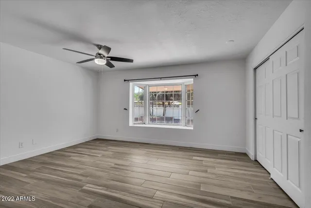 a view of an empty room with a window and wooden floor