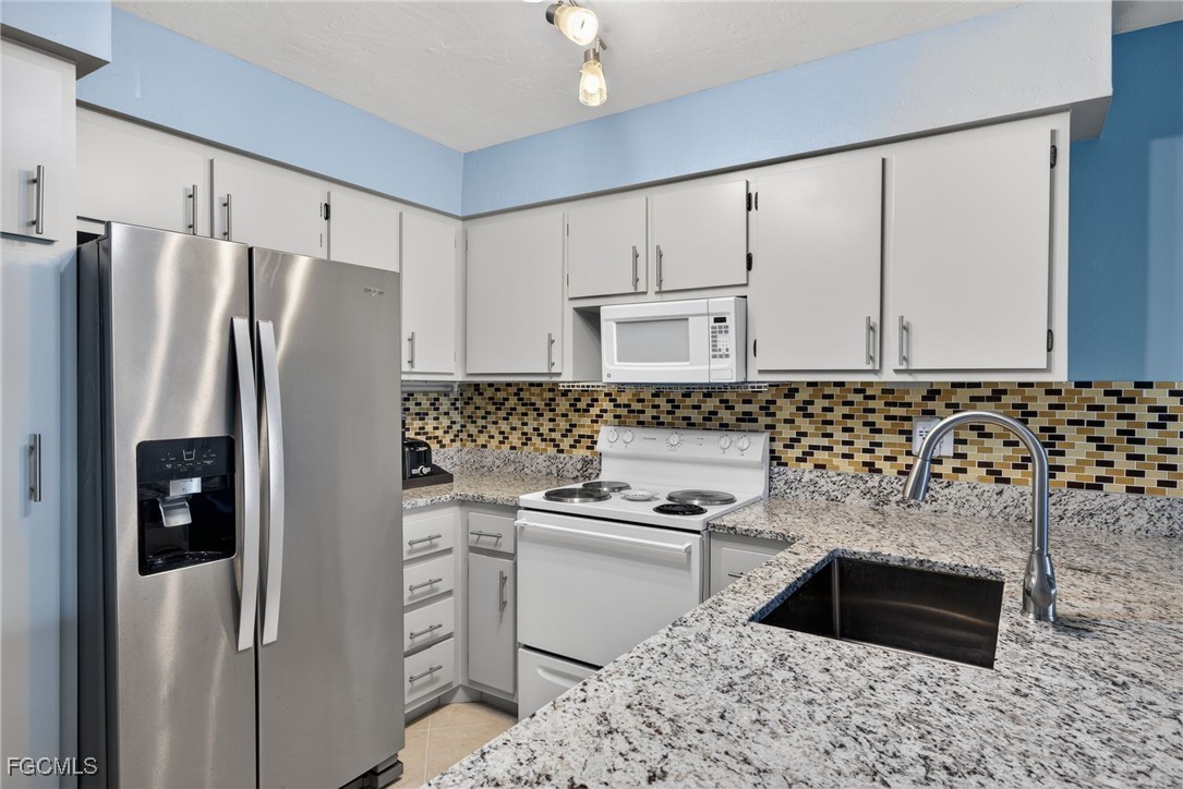 1100 Pondella Road, Unit 811 Cape Coral, FL 33909 - Photo 2 of 24 a kitchen with granite countertop a refrigerator sink and cabinets